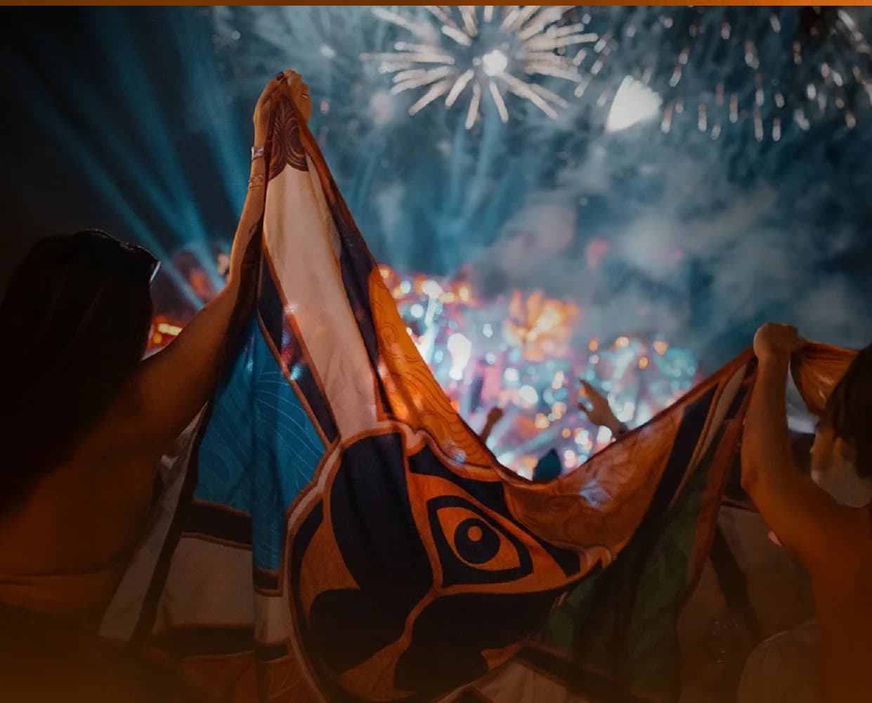 A flag held up against fireworks over the festival grounds